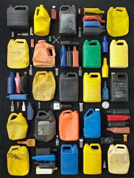 0ne gallon anti-freeze bottles with quart oil bottles and medical and alcohol bottles on black background