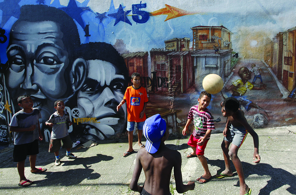 Children play in front of graffiti painted by artists of OPNI, an organization that uses graffiti to improve life in the slums, in the Vila Flavia favela of Sao Paulo August 27, 2011. OPNI, a Portuguese acronym which means "Unidentified Graffiti Artists", was formed in 1997 by some 20 youths in Sao Paulo's marginal slums with the goal of transforming the streets into an open-air gallery where the community can express its gripes and denounce social injustices. With only three of the original founding members left after most were either arrested, abandoned the activity to do something else or died from drug abuse, OPNI offers workshops in art, capoeira dance and graffiti to the community. Their current project is called "Favela Graffitada" and the organization has extended invitations to national and international artists to create over 100 graffiti works throughout the favela. Picture taken August 27, 2011. REUTERS/Nacho Doce (BRAZIL - Tags: SOCIETY WEALTH EDUCATION)