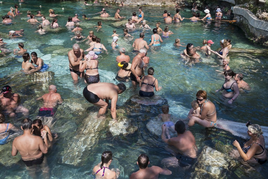Tourists are swimming in the Antique Pool of the ancient Greco-Roman city Hierapolis, near the famous Pamukkale hot springs in southwestern Turkey. In Roman times, thousands of people used to come to the baths, of which there were more than 15. Today's Antique Pool was shaped by an earthquake in the 7th century CE. Tourism is and has been a major industry here. Most of the visitors are Russians. Hierapolis is a UNESCO World Heritage Site. From the series 'Mediterranean. The Continuity of Man' ©Nick Hannes